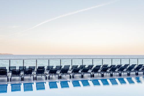 a row of chairs next to the ocean at Melia Alicante in Alicante