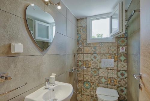 a bathroom with a sink and a mirror and a toilet at Rose House and Apartments in Andiparos