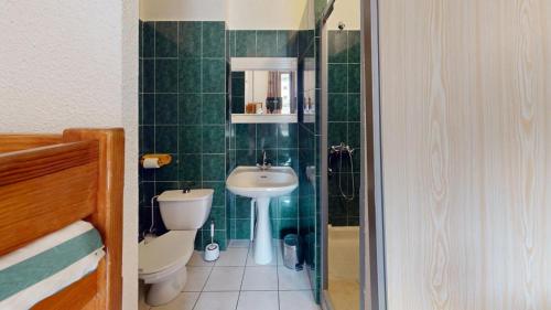 a green tiled bathroom with a toilet and a sink at Les Neiges in Saint-Sorlin-dʼArves
