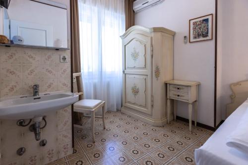La salle de bains est pourvue d'un lavabo, d'une table et d'une armoire. dans l'établissement Hotel Villa Margherita, à Limone sul Garda