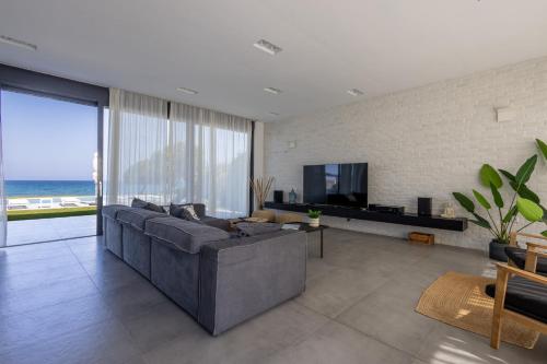 a large living room with a couch and a tv at Liam Beach Front Luxury Villa with 100m2 infinity pool in Phanaes