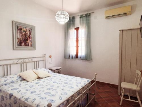 a bedroom with a bed and a chair and a window at Villa Migliore in Lampedusa