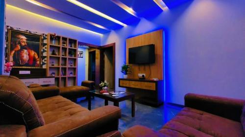 a living room with couches and a tv and blue lights at Sweet Water Villa in Panchgani