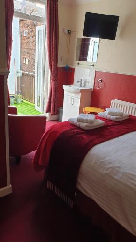 a bedroom with a bed with red walls and a window at All Seasons Guest House in Great Yarmouth