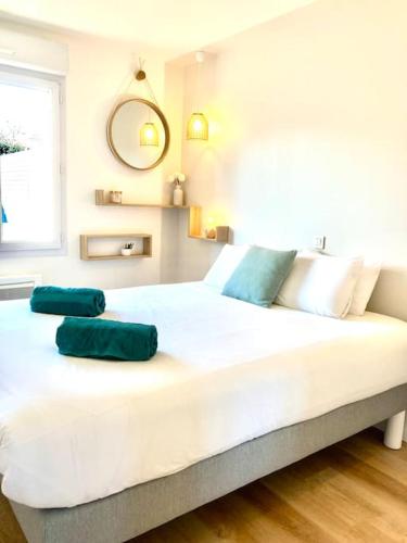 - un grand lit blanc avec 2 oreillers verts dans l'établissement Maison spacieuse avec jardin à 25min des Sables, à Venansault