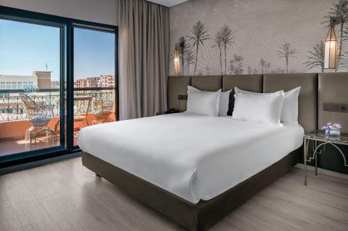a large bed in a hotel room with a large window at Red Hotel Marrakech in Marrakech