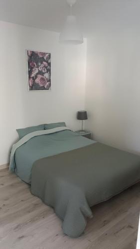 - une chambre blanche avec un lit vert dans l'établissement Maisonnette indépendante, à Montroy