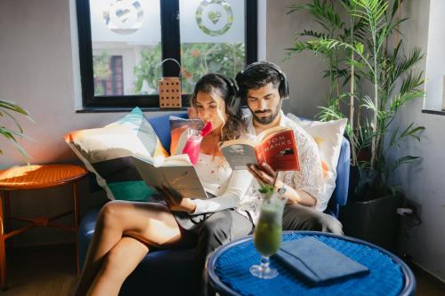 a man and woman sitting on a couch reading books at Hyatt Ronil Goa - a JdV by Hyatt Hotel in Calangute