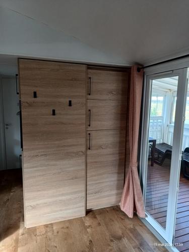 un grand placard en bois dans une pièce avec une porte vitrée dans l'établissement Camping siblu à Valras plage, à Valras-Plage