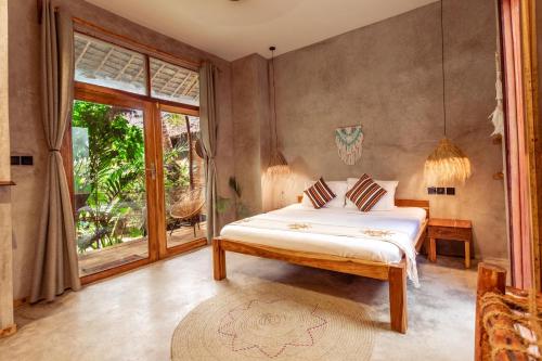 a bedroom with a bed and a large window at The Garten Living in Paje