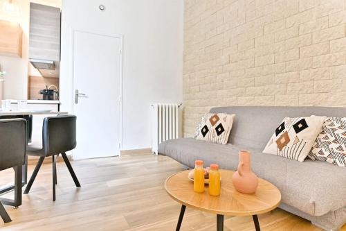un salon avec un canapé et une table dans l'établissement Appartement 2 chambres Pyrénées Alexandre Dumas, à Paris