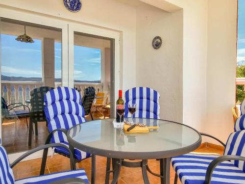 una mesa de cristal con sillas azules y una botella de vino en Casa Lourdes, en Yeste