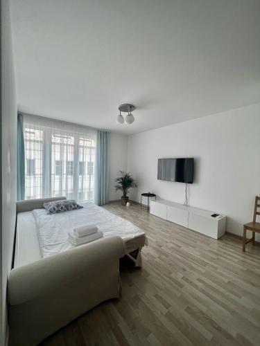 a white bedroom with a bed and a flat screen tv at MT Suites ApartHotel in Budapest