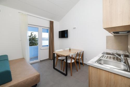 a small kitchen with a table and a sink at Apartments Medena in Trogir