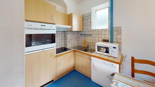 a kitchen with wooden cabinets and white appliances at Les Neiges in Saint-Sorlin-dʼArves