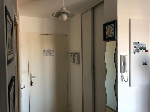 - un couloir avec une porte blanche et un réfrigérateur dans l'établissement Appartement plein centre de La Teste-de-Buch, à La Teste-de-Buch
