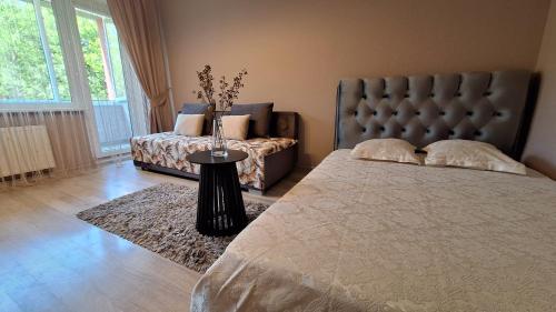 a bedroom with a bed and a couch and a table at Apartamentai su balkonu in Klaipėda