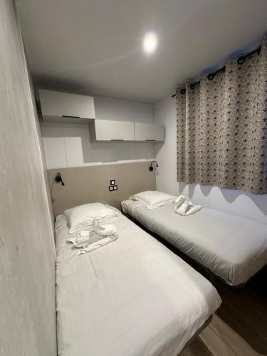 two beds in a room with white sheets at Les collines de lava in Appietto