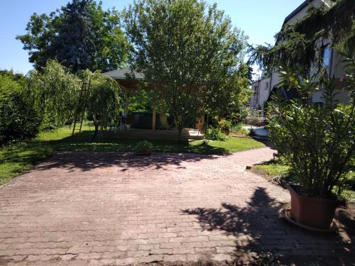 a brick driveway in front of a house with trees at Kokó Panzió in Harkány