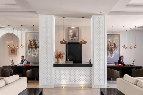 two people sitting at desks in a room with columns at Red Hotel Marrakech in Marrakech
