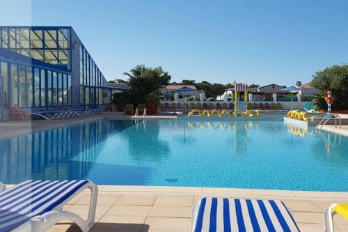 - une grande piscine avec des chaises dans un complexe dans l'établissement Mobil home 4 pers dans camping 5 étoiles avec piscine et accès plage direct, à Bretignolles-sur-Mer