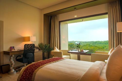 a hotel room with a bed and a desk and a window at Narayani Heights Hotel & Resort in Ahmedabad