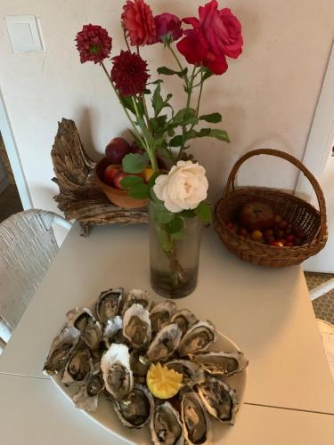 une assiette d'huîtres sur une table avec un panier de fleurs dans l'établissement Studio Centre Ville, à Arcachon