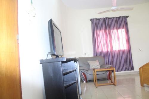 - un salon avec une télévision au-dessus d'une commode dans l'établissement Residence Diane, à Ouagadougou