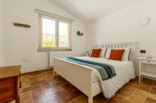 a white bedroom with a bed and a window at Villa Stefanina - Vista mare e piscina privata vicina alla spiaggia di Cala Sinzias in Castiadas