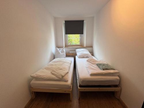 two beds in a small room with a window at Woody Cabin in Buttelstedt