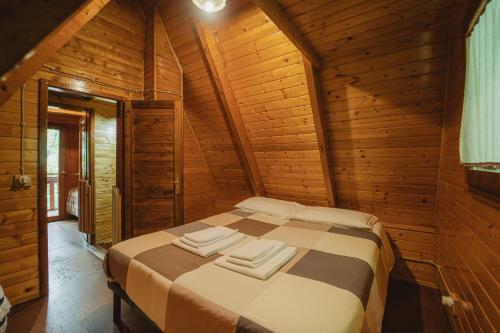 a bed in a wooden room with two towels on it at Matilde's Chalet Etna Nature House in Nicolosi