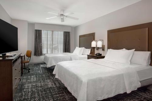 a hotel room with two beds and a flat screen tv at Homewood Suites by Hilton Lackland AFB/SeaWorld, TX in San Antonio