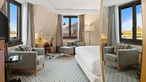 a hotel room with chairs and a couch and windows at Hilton Dresden an der Frauenkirche in Dresden