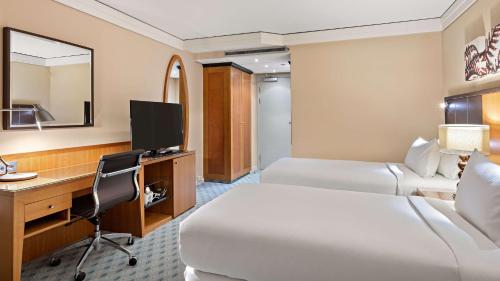a hotel room with two beds and a desk at Hilton Dresden an der Frauenkirche in Dresden