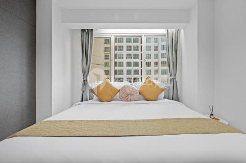 Bett mit Kissen in einem Zimmer mit Fenster in der Unterkunft Vesta by Kozystay - Gandaria in Jakarta
