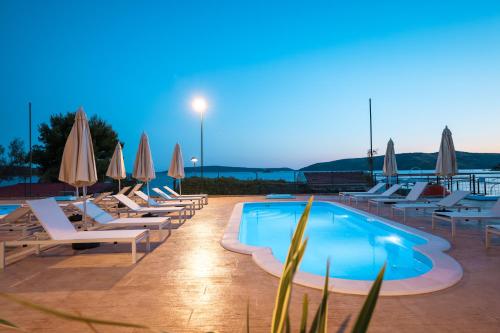 a pool with lounge chairs and umbrellas at a resort at Apartments Medena in Trogir