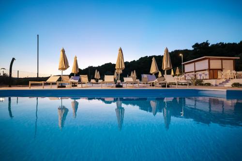 a swimming pool with umbrellas and tables and chairs at Apartments Medena in Trogir