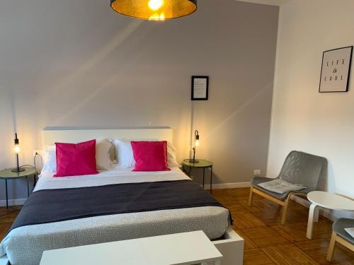 Un dormitorio con una cama con almohadas rosas y una silla en Milano 71 en Milán