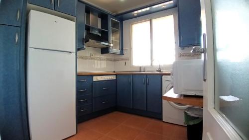 a kitchen with blue cabinets and a white refrigerator at San Fausto in Aguadulce