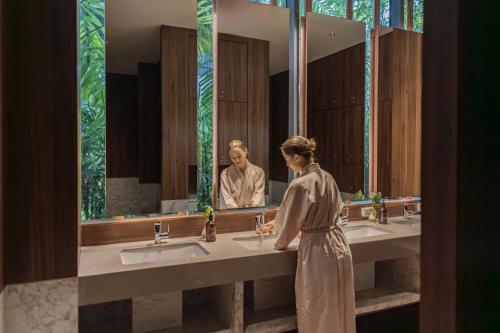 a woman standing in front of a bathroom mirror at Stay Wellbeing & Lifestyle Resort in Rawai Beach
