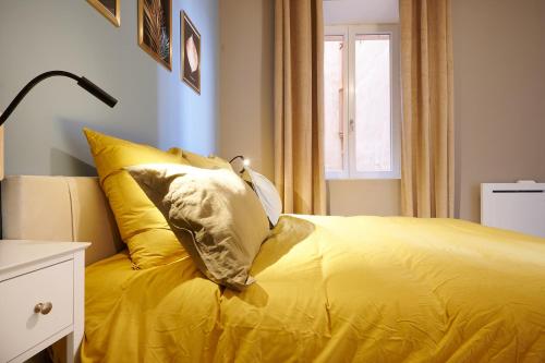 a yellow bed with two pillows on top of it at Le Flourens by Paul Riquet 1609 Residences in Béziers
