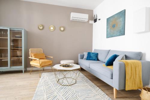 a living room with a blue couch and a chair at Le Flourens by Paul Riquet 1609 Residences in Béziers
