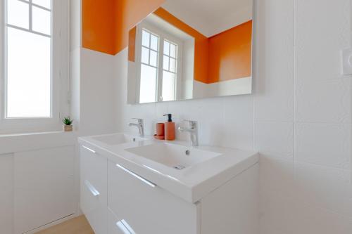 une salle de bain blanche avec un lavabo et un miroir dans l'établissement Appartement Spacieux - Vue Pyrénées - Hypercentre, à Tarbes