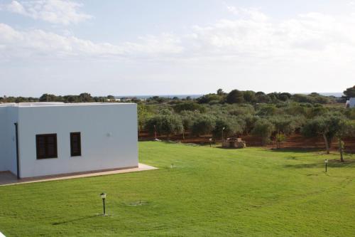 a white building in a field of green grass at Le Casette a Favignana in Favignana