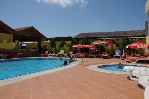 una piscina con sedie, ombrelloni e persone di Sun Flower Apart Hotel a Side