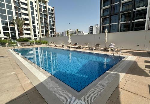 a large swimming pool with chairs and umbrellas at EasyGo - Unbeatable Deals on Urban Rentals in Riviera 16 in Dubai