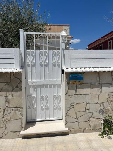 a white gate on a stone wall with a stone wall at Holiday Rooms Ninfa in Avola