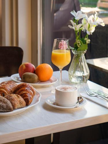 a table with plates of food and a glass of orange juice at Hotel Parc Plaza in Luxembourg