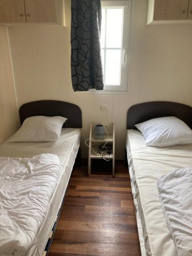 deux lits dans une chambre avec une fenêtre dans l'établissement Mobil home 4 pers dans camping 5 étoiles avec piscine et accès plage direct, à Bretignolles-sur-Mer
