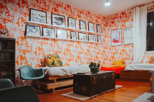 a living room with an orange wall with pictures at Ostello Bello Milano Centrale in Milan